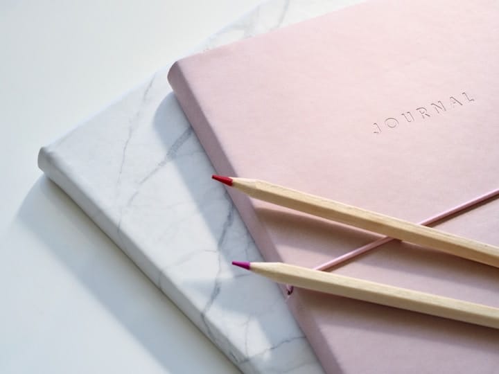 A serene hand writing journal on a bed